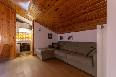 a living room with a couch and a kitchen at Casa Val di Fassa in Canazei