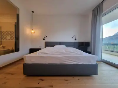 a bedroom with a large bed with a large window at Pitla Cuna - Eco Relais in Terlano