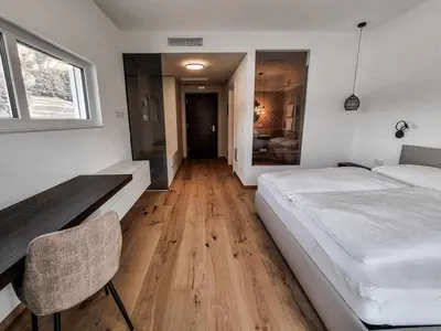 a bedroom with a large white bed and a desk at Pitla Cuna - Eco Relais in Terlano