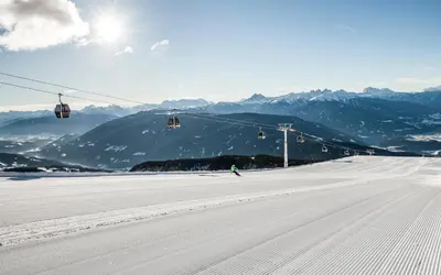 a person is skiing down a snow covered slope with a ski lift at Peintnerhof Appartments & Zimmer in Naz-Sciaves
