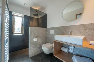 a bathroom with a sink and a toilet and a mirror at Peintnerhof Appartments & Zimmer in Naz-Sciaves