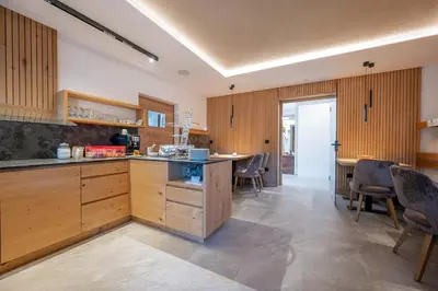 a kitchen with wooden cabinets and a table and chairs at Peintnerhof Appartments & Zimmer in Naz-Sciaves