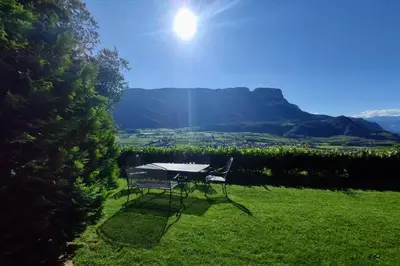 a table and chairs sitting on a lawn with the sun at Bühel im Gschleier in Appiano sulla Strada del Vino