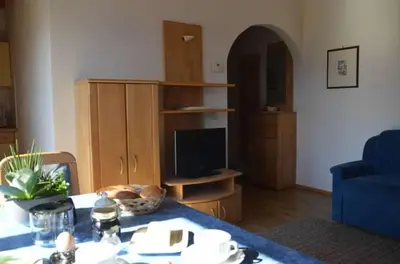 a living room with a table and a blue chair at Bühel im Gschleier in Appiano sulla Strada del Vino