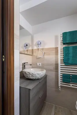 a bathroom with a stone sink and green towels at Cortina Comfort House in Cojana