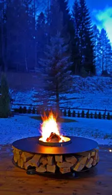 a fire pit in the middle of a snow covered yard at Chalet La Ciaseta in Pozza di Fassa