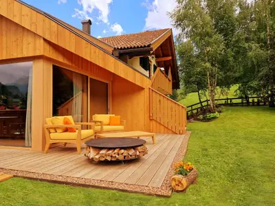 a house with a wooden deck with a table and chairs at Chalet La Ciaseta in Pozza di Fassa