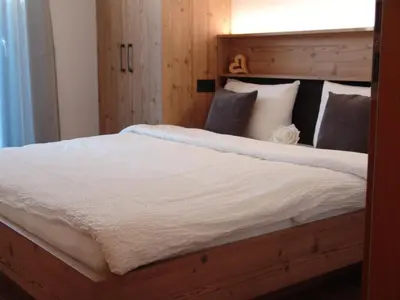 a bedroom with a large bed with a wooden headboard at Lampenhof in Brunico