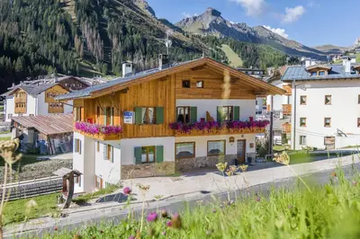 a house in a village with mountains in the background at Affittacamere Blank in Arabba