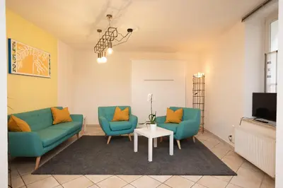 a living room with two blue chairs and a table at Suite - Sweet MayLeen in Merano