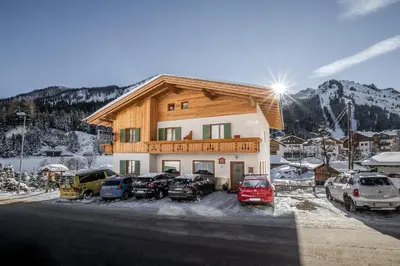 a building with cars parked in a parking lot at Appartamento Blank in Arabba