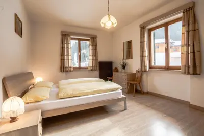 a bedroom with a bed and a desk and windows at Appartamento Blank in Arabba