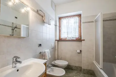 a white bathroom with a sink and a toilet at Appartamento Blank in Arabba