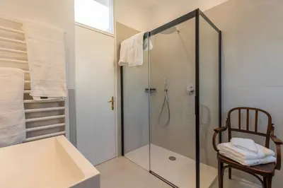 a bathroom with a glass shower with a chair at Villa Stubai - Penthouse in the heart of Merano in Merano