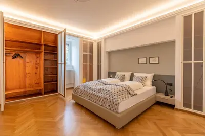 a bedroom with a large bed and wooden floors at Villa Stubai - Penthouse in the heart of Merano in Merano