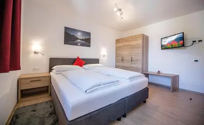 a bedroom with a large bed with white sheets and red pillows at MOUNTAIN RESIDENCE ALPENHOF - company Hotel Alpenhof KG sas der Gasser Renate in Bressanone