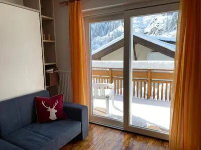 a living room with a couch and a sliding glass door at Amalia Apartment in Santa Cristina in Val Gardena