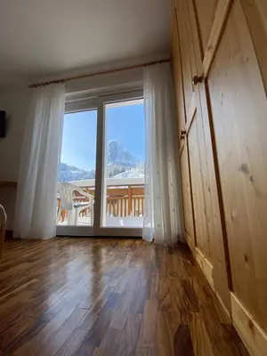 an empty room with a large window and a wooden floor at Amalia Apartment in Santa Cristina in Val Gardena