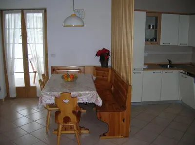 a kitchen with a table and chairs and a kitchen with a sink at Appartamento Zorzi in Ziano di Fiemme
