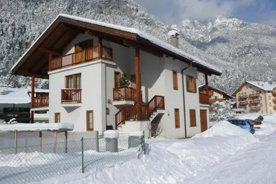 a house with a balcony in the snow at Appartamento Zorzi in Ziano di Fiemme