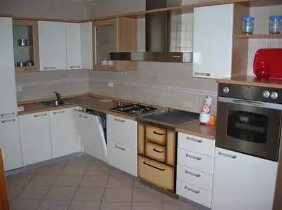 a kitchen with white cabinets and a stove top oven at Appartamento Zorzi in Ziano di Fiemme