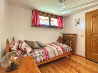 a bedroom with a bed and a table and a window at El Fogher in San Vito di Cadore