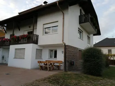 a white house with a wooden table in front of it at Haus Ebner Eppan an der Weinstraße St Pauls in Appiano sulla Strada del Vino