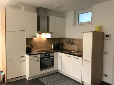 a kitchen with white cabinets and a sink at Schöne Neubauwohnung mit Garten in Merano