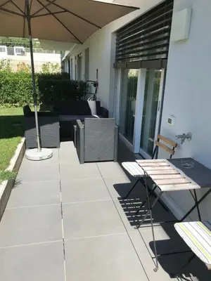 a patio with a table and an umbrella at Schöne Neubauwohnung mit Garten in Merano