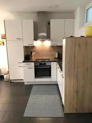 a kitchen with white cabinets and a stove top oven at Schöne Neubauwohnung mit Garten in Merano