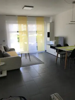 a living room with a couch and a table at Schöne Neubauwohnung mit Garten in Merano