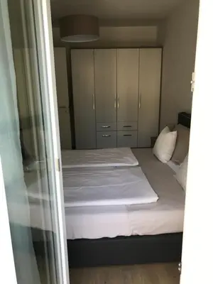 a small bedroom with two beds and white cabinets at Schöne Neubauwohnung mit Garten in Merano