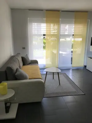 a living room with a couch and a table at Schöne Neubauwohnung mit Garten in Merano