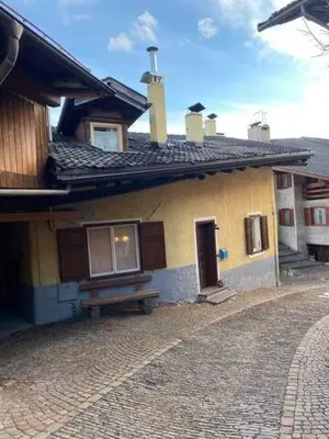 a yellow house with a bench in front of it at Casa Mia Fiemme in Carano