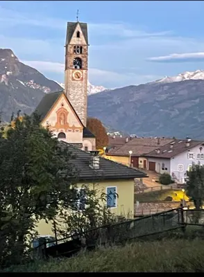 a church with a tower with a clock on it at Casa Mia Fiemme in Carano