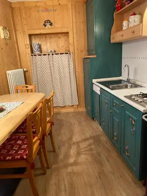a kitchen with green cabinets and a wooden table at Casa Mia Fiemme in Carano