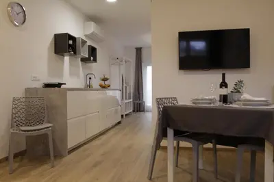 a kitchen and dining room with a table and a tv on the wall at Apartment Mia in Merano