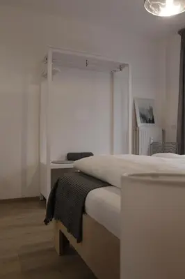 a white bedroom with a bed and a table at Apartment Mia in Merano