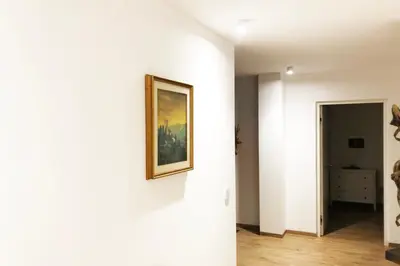 a hallway with white walls and a painting on a wall at Laurentia Penthouse Apartment in Merano