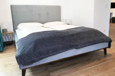 a bed with a gray blanket and pillows on it at Laurentia Penthouse Apartment in Merano