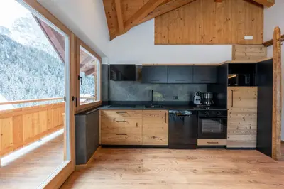 a kitchen with wooden cabinets and a large window at Orchidea Suite & SPA Apartments in Canazei