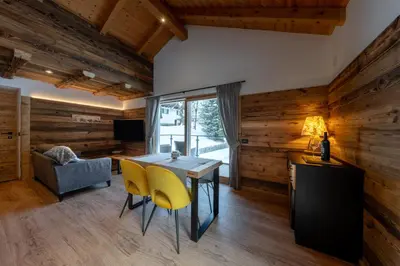 a dining room with wooden walls and a table and yellow chairs at Orchidea Suite & SPA Apartments in Canazei