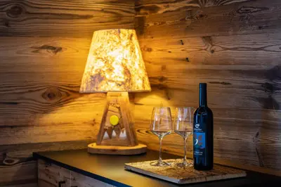 a table with a bottle of wine and two wine glasses at Orchidea Suite & SPA Apartments in Canazei