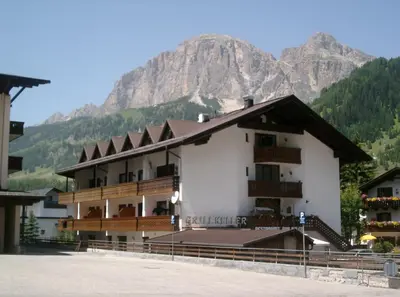 a large building with a mountain in the background at GARNI AQUILA in Corvara in Badia