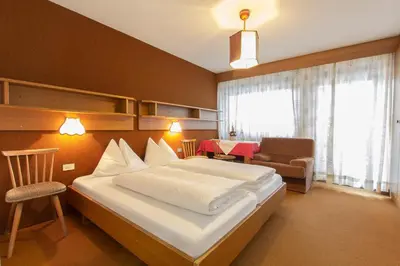 a bedroom with a bed and a chair and a table at GARNI AQUILA in Corvara in Badia