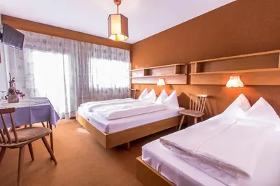 a hotel room with two beds and a table at GARNI AQUILA in Corvara in Badia