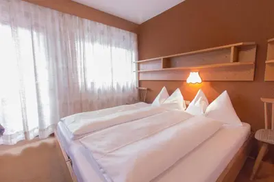 a bedroom with a large white bed with a window at GARNI AQUILA in Corvara in Badia