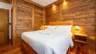 a bedroom with a white bed with wooden walls at Hotel Oasi in San Vito di Cadore