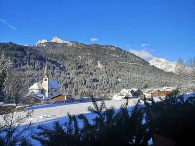 a small village with a church in the snow at Hotel Oasi in San Vito di Cadore