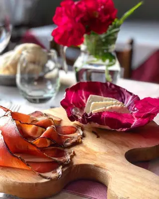 a wooden cutting board with a piece of food and flowers at Hotel Oasi in San Vito di Cadore